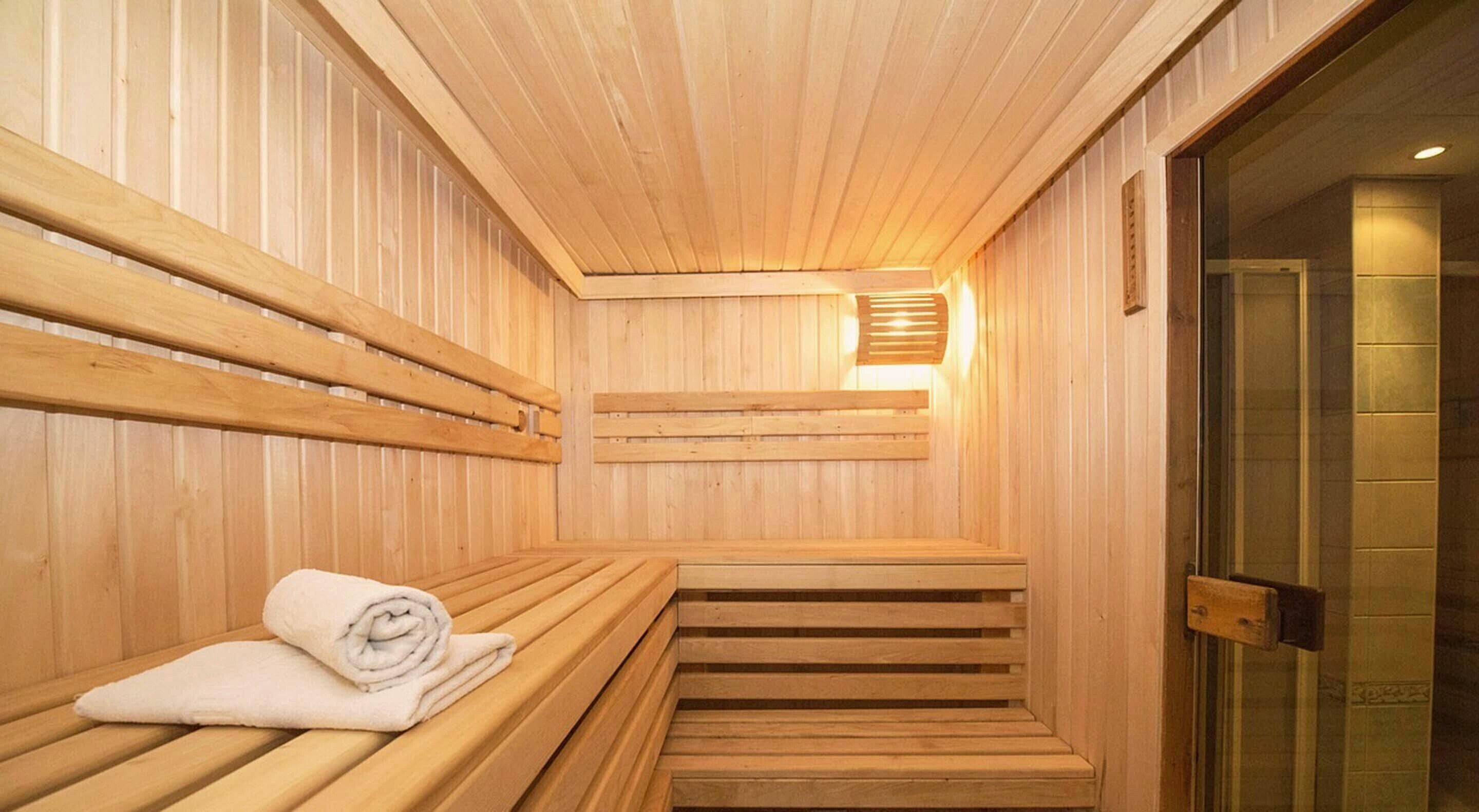 Un sauna en bois avec des bancs et une serviette posée sur l’un des côtés.