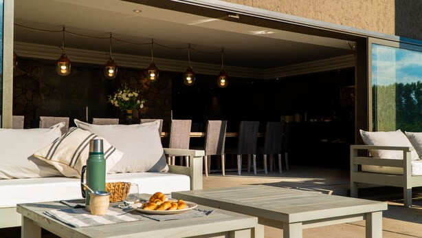 An outdoor seating area with a sofa, chairs, and a table with food. - Casa Septem (Tunuyan)
