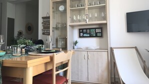 Un coin repas avec une table en bois, des chaises et un buffet portant l’inscription « BAR », contenant des verres et une horloge.