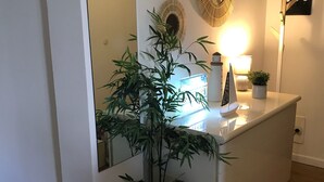 Une salle de bain moderne avec un meuble-lavabo blanc, un grand miroir, une plante en bambou, un élément décoratif mural et un panneau indiquant « Il est temps de rêver ».