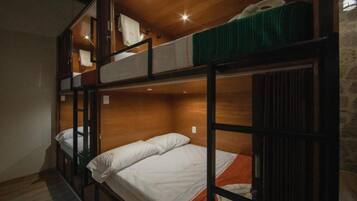 A bunk bed room with wooden walls and a stone wall on one side.