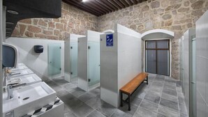 A public restroom with multiple sinks, a bench, and a stone wall. - OYO Hostal Mich Morelia (Morelia)
