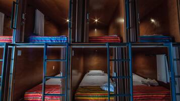 A multi-level bunk bed room with wooden walls and metal railings.