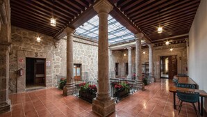 A spacious interior with stone walls, a tiled floor, and a central column. There are tables and chairs, and a staircase is visible in the background. - OYO Hostal Mich Morelia (Morelia)