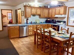 A kitchen with wooden cabinets, a dishwasher, a dining table with chairs, and a stove.