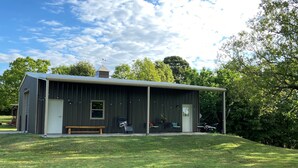 A modern metal building with a covered porch, a bench, and a small table. - AMAZING VIEW of Mount Magazine! (Booneville)