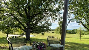 Two outdoor metal chairs with cushioned seats and backs, placed on a concrete patio with a flower arrangement between them. - AMAZING VIEW of Mount Magazine! (Booneville)