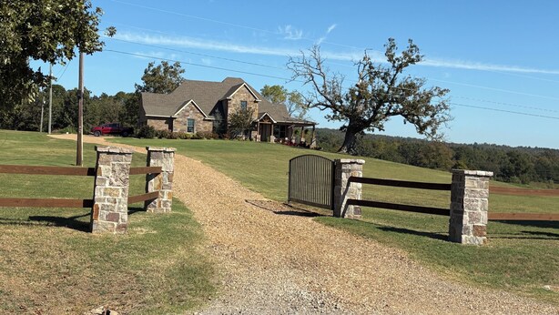 A stone gate leading to a house with a stone facade and a covered porch. - AMAZING VIEW of Mount Magazine! (Booneville)