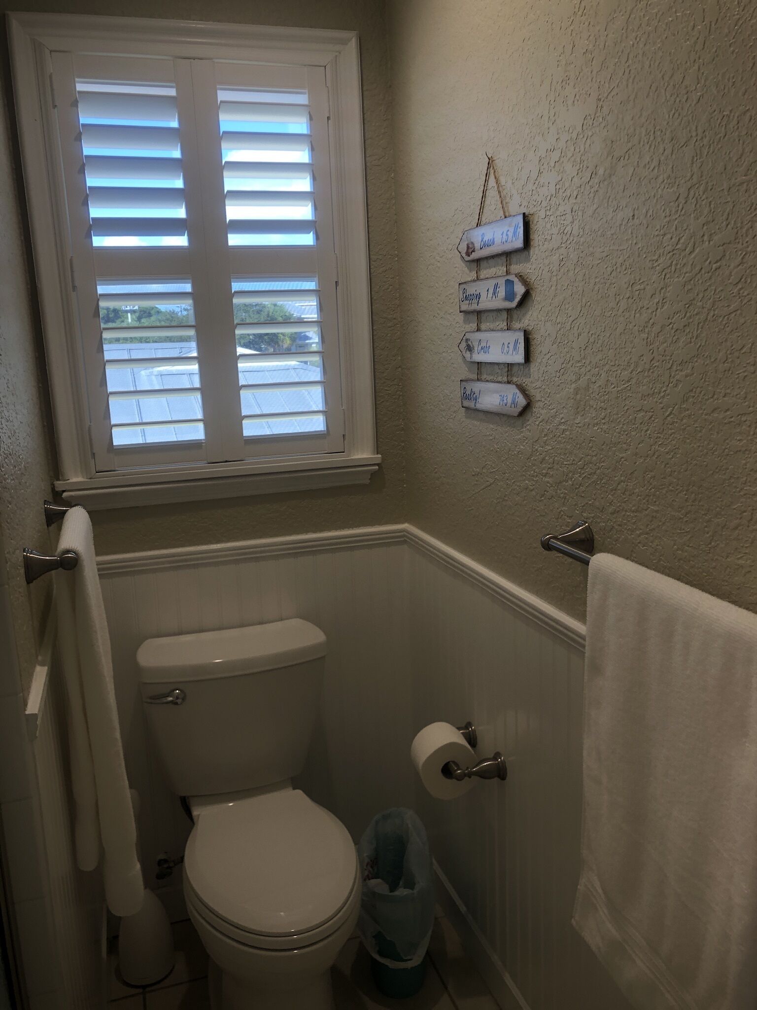Een badkamer met toilet, bidet, handdoekhouder en een raam met zonwering.