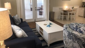 Olohuoneessa on sohva, sohvapöytä ja kuviollinen nojatuoli. Siellä on myös ruokailutila, jossa on pöytä ja tuolit.
