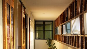 A hallway with wooden doors and windows, a tiled floor, and a potted plant. - Madre Tierra Hotel & Coworking & Hostal (Puerto Escondido)
