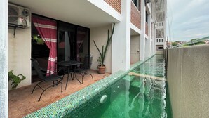 A rooftop pool with a tiled edge, a table and chairs, and a potted plant. - Madre Tierra Hotel & Coworking & Hostal (Puerto Escondido)