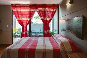 Un dormitorio con cama, cortinas rojas, vistas al exterior y una obra de arte colgada en la pared.