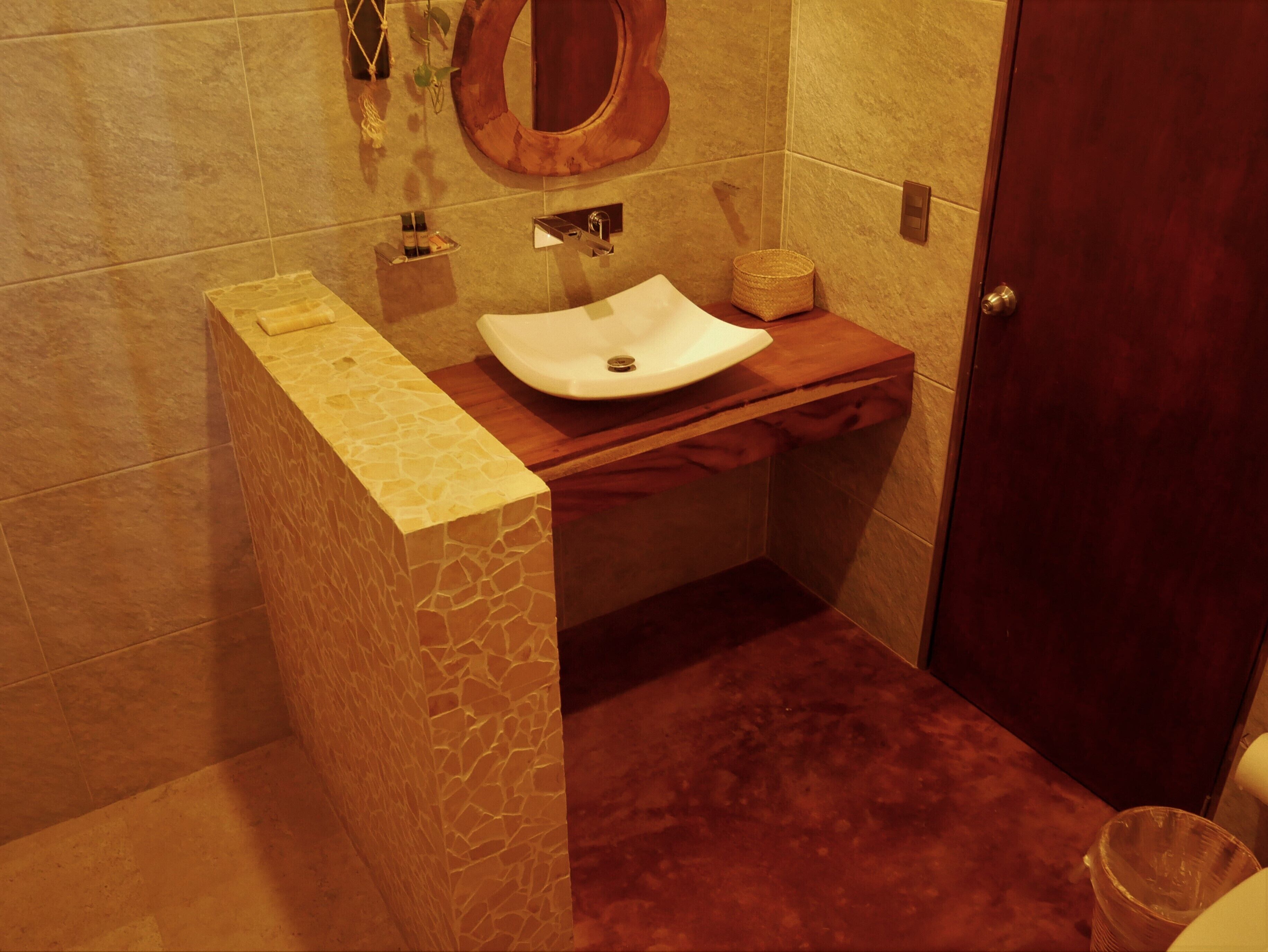 Un baño con lavamanos de piedra, tocador de madera y puerta de madera.