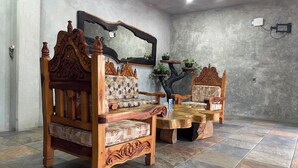 A room with two wooden sofas and a matching coffee table, a large mirror, and a small plant on the wall. - Madre Tierra Hotel & Coworking & Hostal (Puerto Escondido)