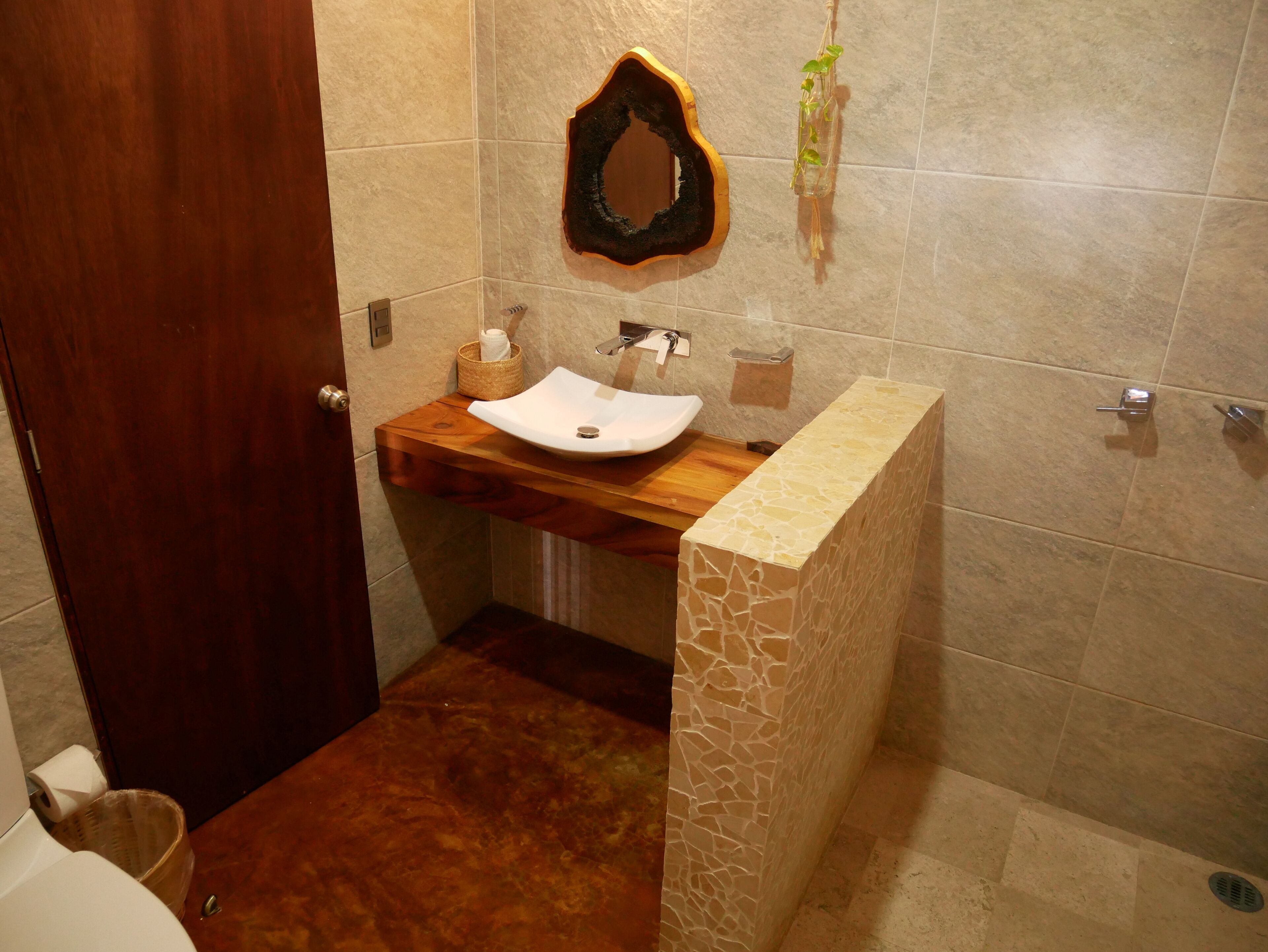 Une salle de bain avec un meuble-lavabo en bois, un lavabo blanc et un miroir décoratif.