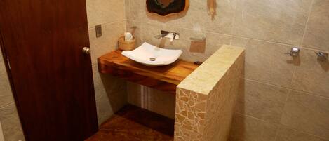 Un baño con tocador de madera, un lavabo blanco y un espejo decorativo.