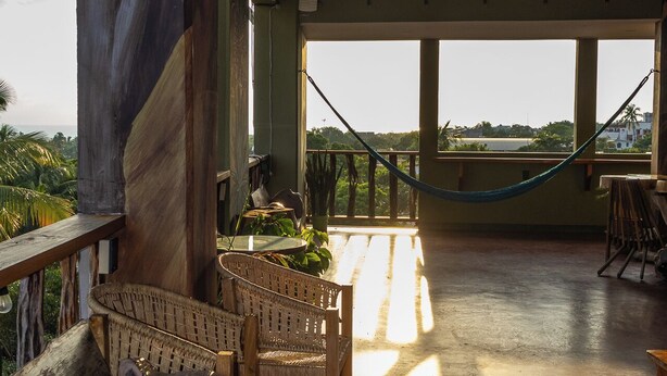 A spacious veranda with a wooden bench, a hammock, and a view of the landscape. - Madre Tierra Hotel & Coworking & Hostal (Puerto Escondido)