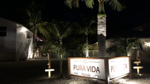 Ein Schild mit der Aufschrift 'PURA VIDA' und einem Palmenbaum im Vordergrund.