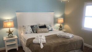 Ein Schlafzimmer mit einem Bett, zwei Nachttischen, Sternfisch-Lampen und einem Fenster.