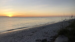 A beach with a clear sky and calm sea at sunset.