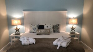 A bedroom with a bed, two nightstands, star-shaped lamps, and a 'SUMMER' pillow.
