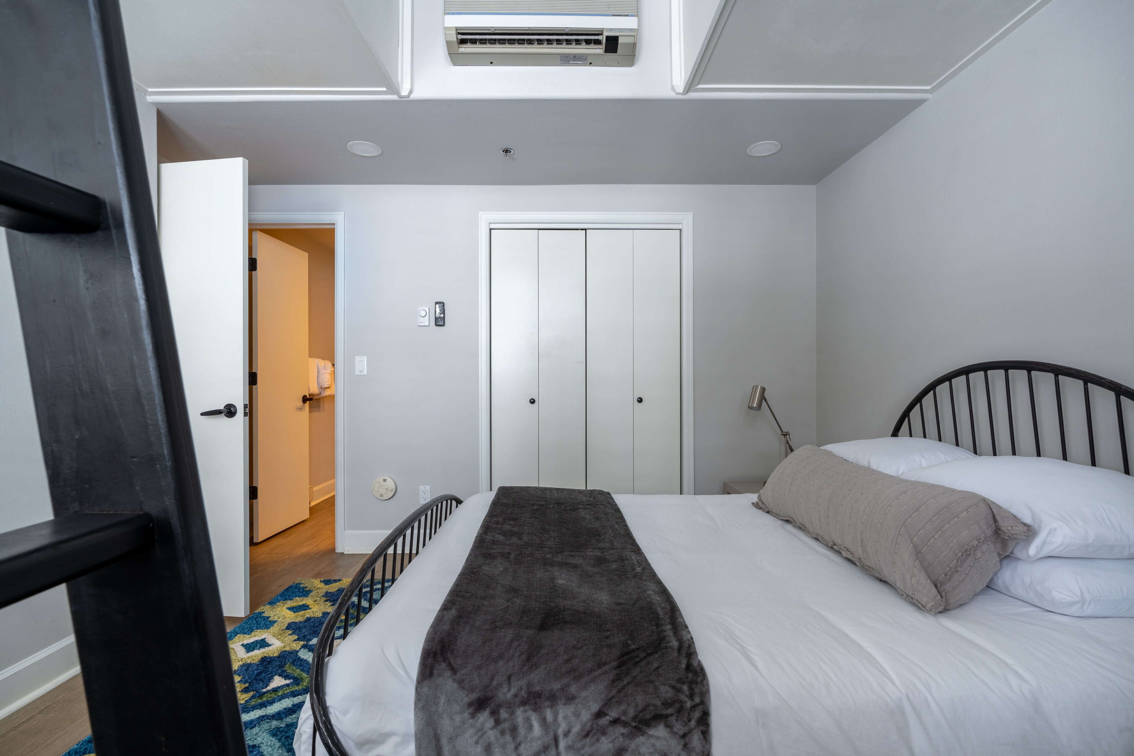 Un dormitorio con cama, armario y aire acondicionado.