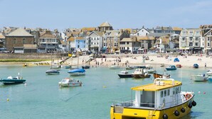 A coastal town with a sandy beach, boats, and historic buildings.