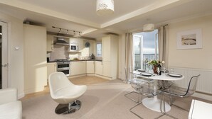 A modern kitchen with a microwave, oven, and gas stove. There is a dining area with a round table and chairs.