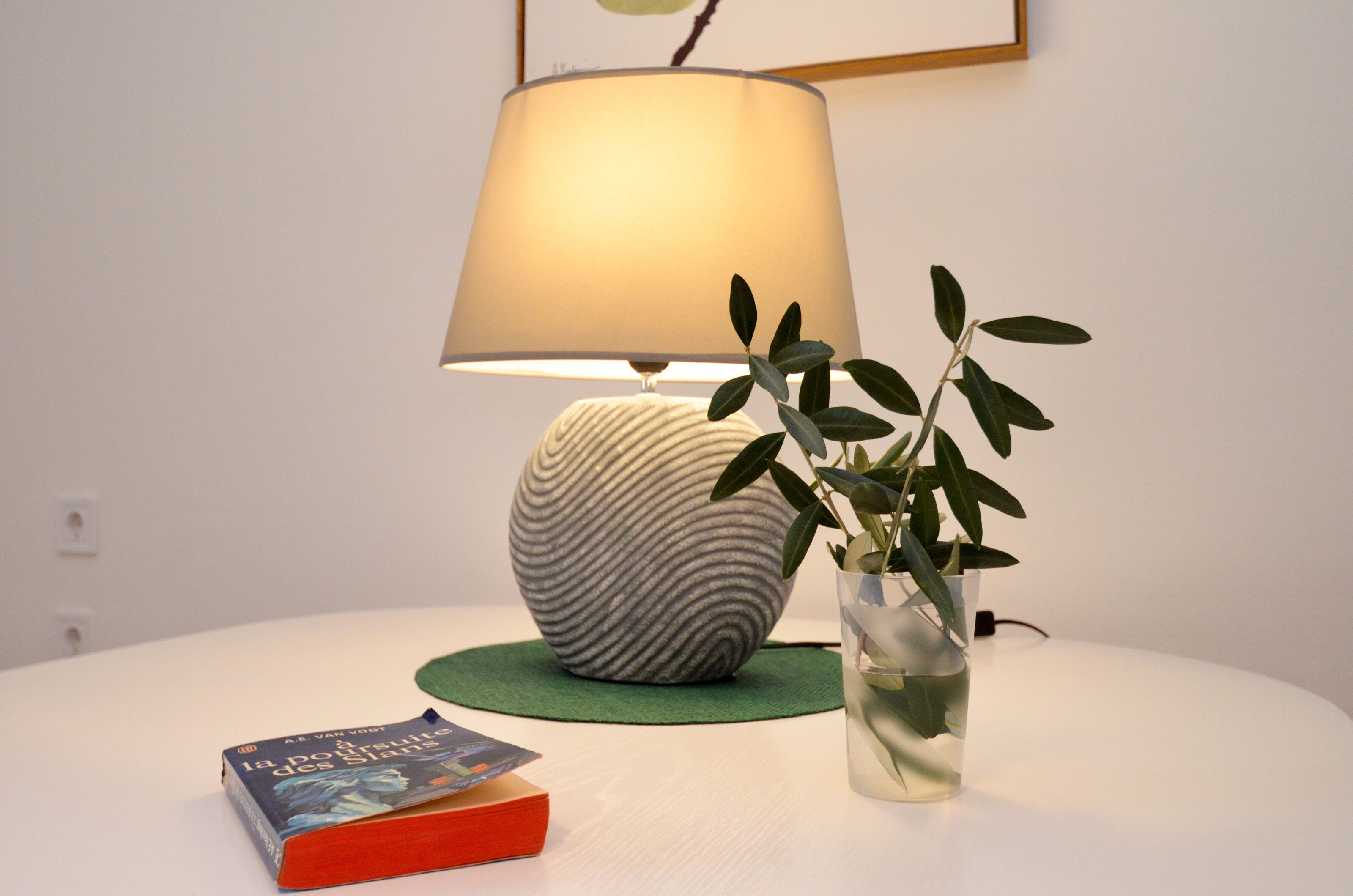 Une table avec une lampe, une plante dans un vase et un livre.