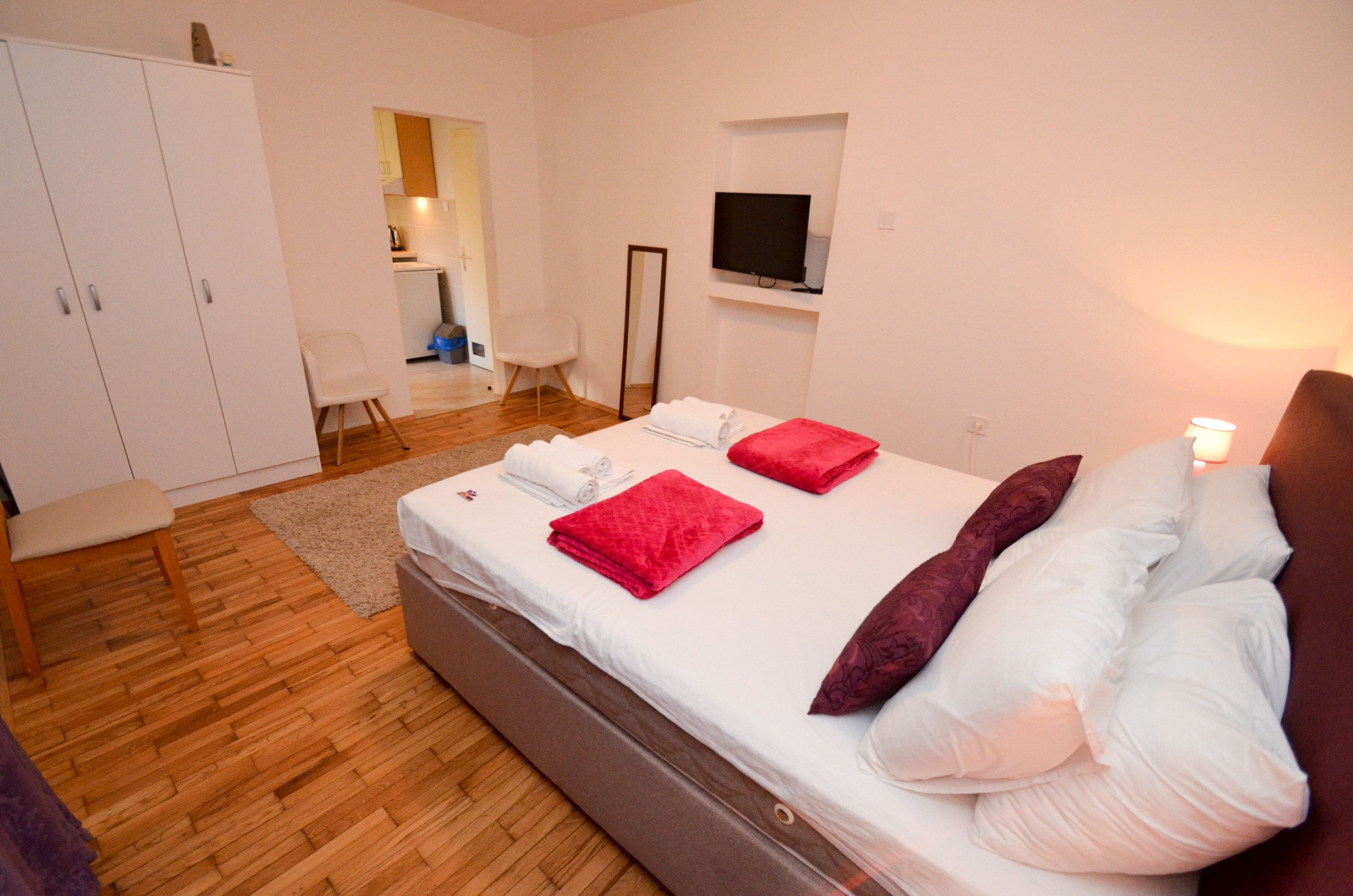 Ein Schlafzimmer mit Bett, Fernseher, Kleiderschrank und kleinem Schreibtisch.