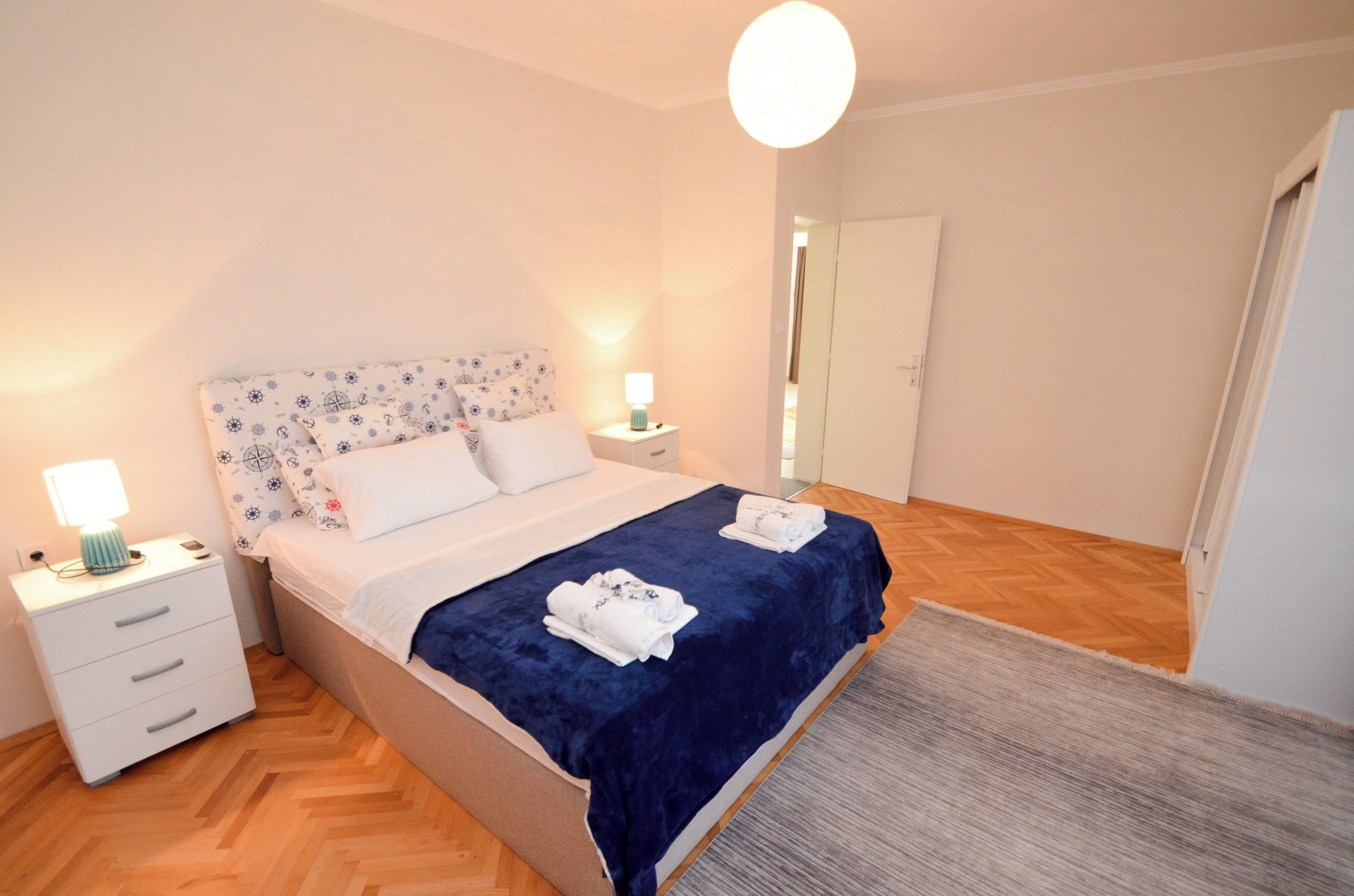 Un dormitorio ordenado con cama, mesitas de noche y espejo.