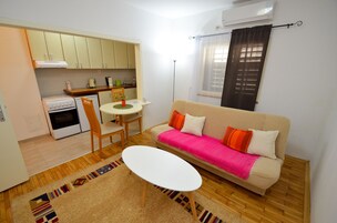 Un espacio habitable compacto con kitchenette, sofá, mesa de comedor y una mesita de centro.