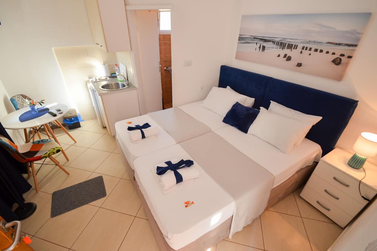 Ein Hotelzimmer mit einem großen Bett, einem Schreibtisch mit Stuhl, einem kleinen Badezimmer und einem Bild an der Wand.