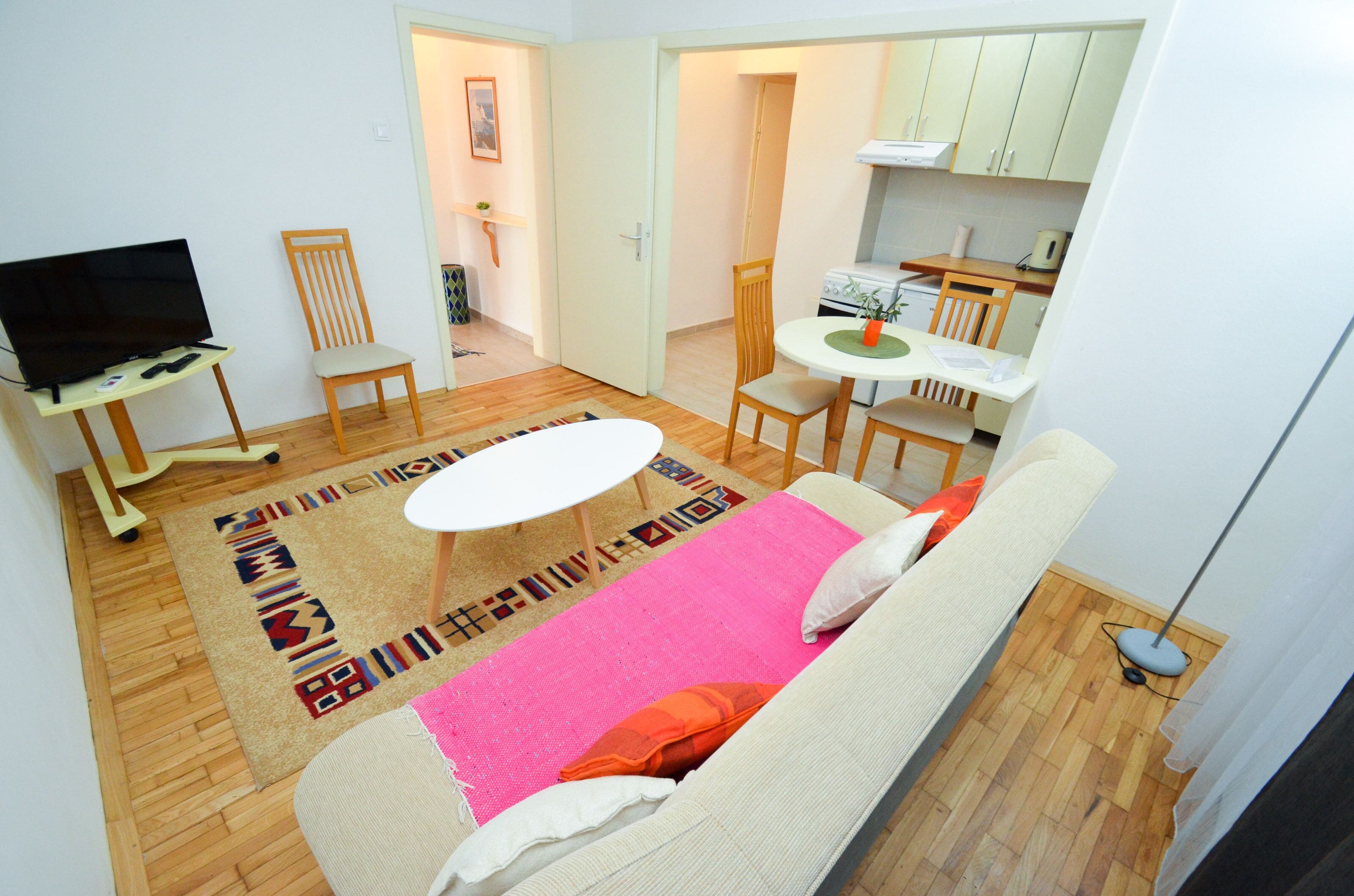 Una sala de estar con sofá, televisor y una zona de comedor con mesa y sillas.