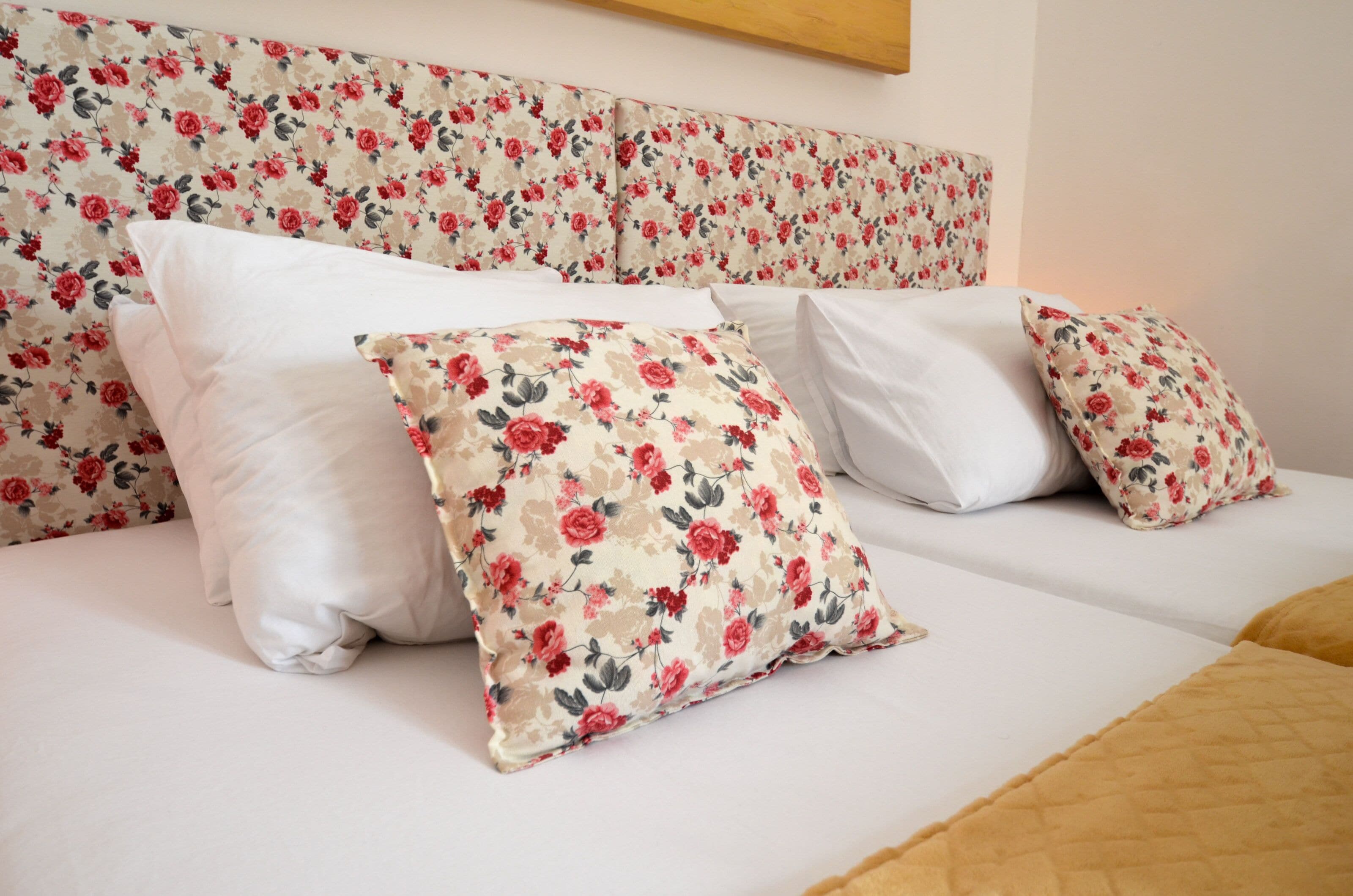Una cama con almohadas de estampado floral y un cabecero con diseño floral.