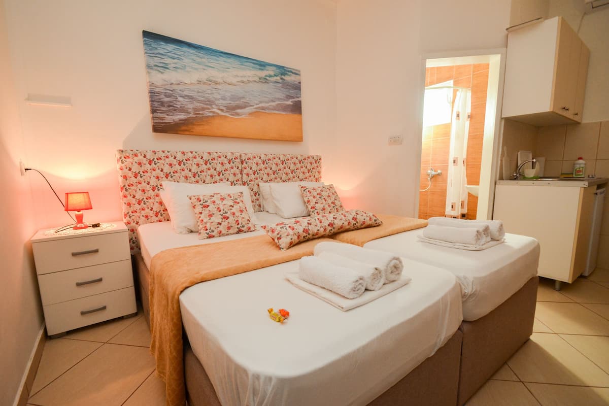 Ein Hotelzimmer mit Bett, Nachttisch, einem Gemälde und einer Küchenzeile.