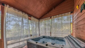 Ein Whirlpool unter einem Holzdach mit Blick auf Bäume.