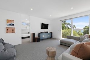 A modern living room with a sofa, a coffee table, a TV, and a view of the outdoors.