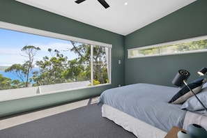 A bedroom with a large window, a bed, and a ceiling fan.