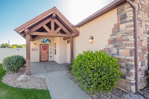 A house with a stone facade, a wooden porch, and a front door with a wreath. - Black Bear IV: 2 King Suites & Dog-Friendly (Fruita)