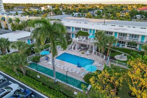 A hotel with a swimming pool, outdoor seating, and a view of the surrounding neighborhood. - One block from Pompano Beach - condo w/ shared heated pool & sundeck (Pompano Beach)