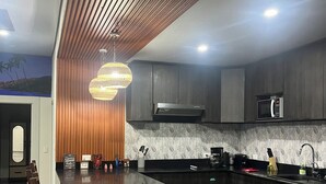 Een moderne keuken met een groot eiland, donkere kastjes en een houten plafond.