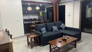 Een moderne woonkamer met een hoekbank, een houten salontafel en een eethoek met stoelen.