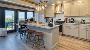 A modern kitchen with a large island, bar stools, and a view to the outdoors. - Welcome to “Stealing Time” – Your Cozy Getaway (Burnside)