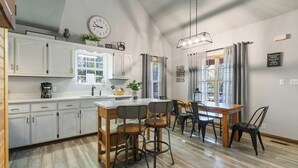 A kitchen with white cabinets, a wooden dining table, and bar stools. - Welcome to “Stealing Time” – Your Cozy Getaway (Burnside)