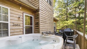 A wooden house with a hot tub on the deck, a barbecue setup, and a sign that reads "Towels". - Welcome to “Stealing Time” – Your Cozy Getaway (Burnside)
