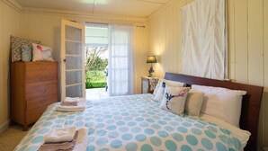 A bedroom with a bed, a dresser, a nightstand, and a window with curtains. - Cox's Cottage in the Hawkesbury Valley (Pitt Town)