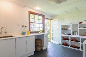 Kitchen features a shelf unit, sink, and wicker basket.
