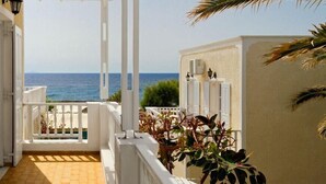 Pasillo con vistas al mar, puertas blancas y un balcón con plantas.